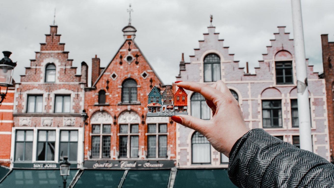 person holding miniature house toy comparing on real building
